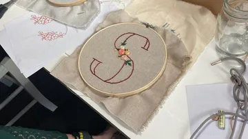 Embroidered letter “S” in an embroidery frame on fabric