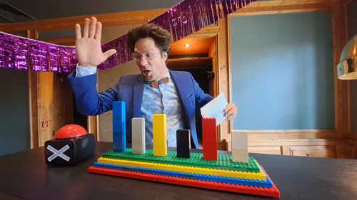 Ein Mann zeigt mit der Hand auf bunte Bauklötze.