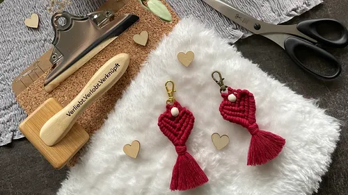 Red keychains lie on a soft surface.