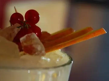 A drink with ice, decorated with fruit and sticks.