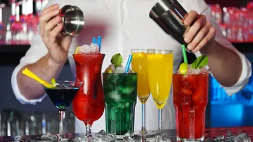 Barkeeper mixt bunte Cocktails hinter der Bar mit Eis.
