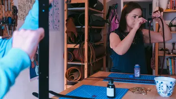A woman ties a ribbon in a workroom.