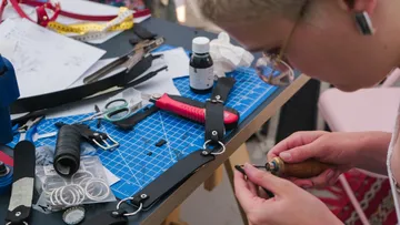 Person working on leather accessories at a table.