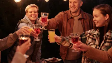 Group of people toast with drinks in a cozy setting.