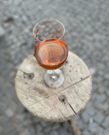 Glass with rosé wine on a wooden outdoor table.