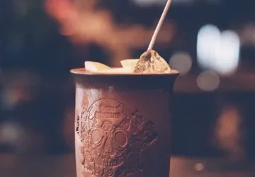 Ein gefüllter Becher mit Eis und Zitrusfrüchten steht zentral.