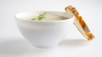 Bowl with creamy soup and a piece of bread.