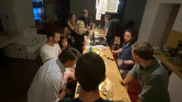 Group of people celebrate at a long table bar.