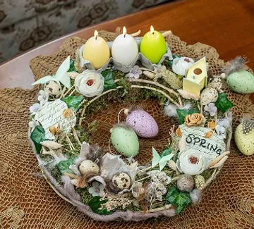 Spring wreath with candles and colorful easter eggs on table.