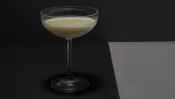 Ein Glas steht auf einer dunklen Oberfläche und enthält Flüssigkeit.