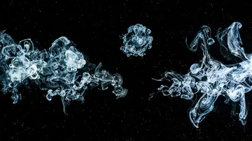 Clouds of smoke float in black space.