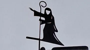 Figure with rod points outside against a light blue sky.