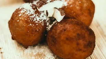 Fried balls with shredded coconut on a wooden surface.