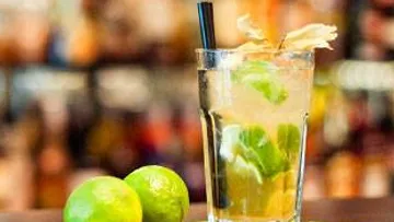 A cocktail with limes is on a table.