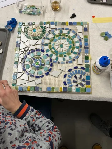 Farbenfrohes Mosaik wird auf einer Arbeitsfläche gelegt.
