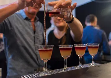 Gläser mit farbigen Cocktails werden an der Bar gefüllt.