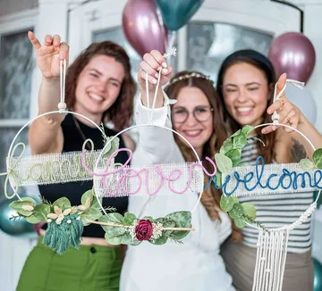 Drei Frauen präsentieren dekorative Schilder mit Worten.