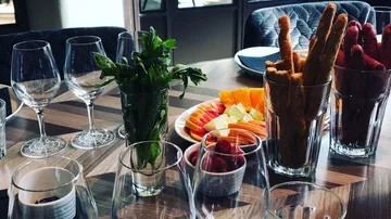 Glasses with fresh ingredients and colorful snacks on table.
