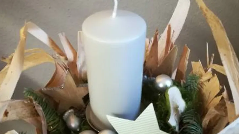 White candle stands in a decorative, natural arrangement.