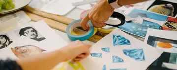 Two hands grab adhesive tape to edit pictures.