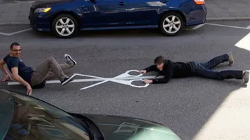 Two people are lying on the street and posing with scissors.