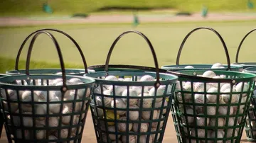 Baskets with golf balls are on the practice ground.