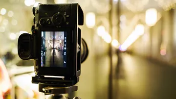 Camera stands on a stand and records illuminated surroundings.