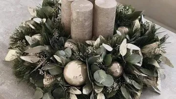 Candles stand in a decorative, green wreath arrangement.