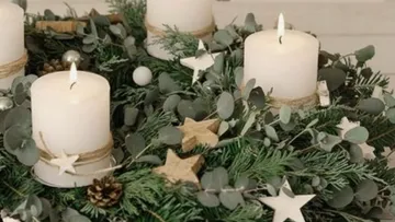 Candles stand on an Advent wreath made of pine branches.