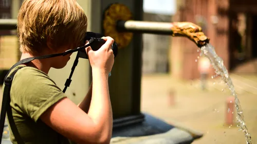 Boy photographs water splashing out of a tap.