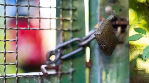 A lock secures a green gate outside.