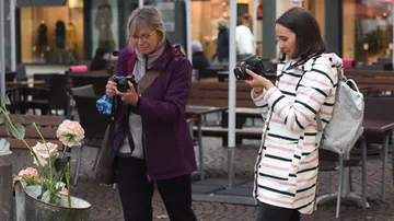 Zwei Frauen fotografieren Blumen in einem Innenhof.