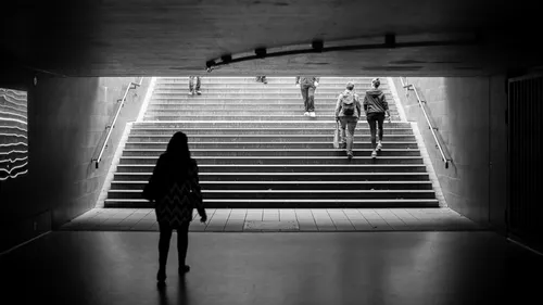 Eine Person steht in einem Tunnel; andere steigen Treppe hoch.