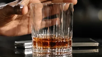 A glass with a drink is held by one hand.