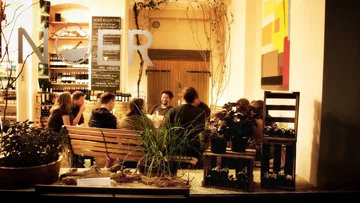 Tables with guests sit relaxed in a wine shop.