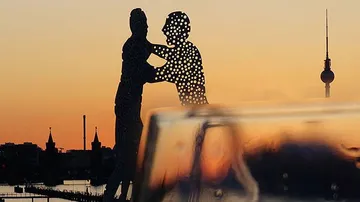 Sculpture depicts dancers silhouetted against sunset.