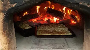 Brotbacken im Holzofen bei flammender Hitze.