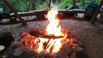 Campfire burning, grill over flames in a forest.
