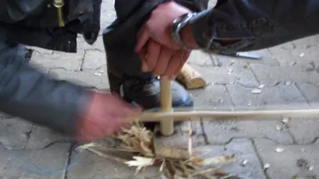 Two hands are working on a piece of wood on the floor.