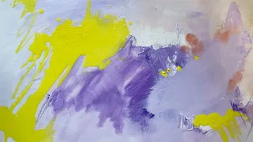 Bunte Farbspritzer auf einer Leinwand mit lila und gelb.