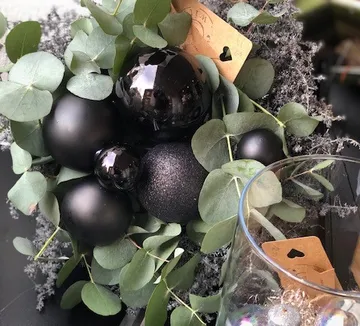 Schwarze Kugeln liegen zwischen grünen Eucalyptusblättern.