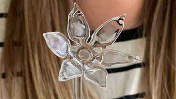 Glasblumenstab wird von einer Person gehalten, gestreifte Kleidung.