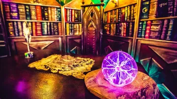 Purple glass ball is lying on a table in a library.