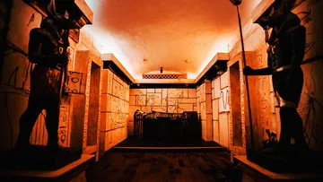 Dark room with statues, religious wall paintings and the theme of Egypt.