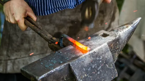 A blacksmith works glowing metal on an anvil.