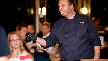 A chef talks and interacts with guests in a restaurant.