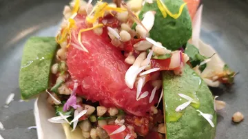 Salad with colorful ingredients, served on a grey plate.