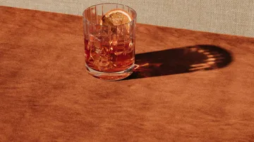 Ein Glas mit Getränk steht auf einem braunen Tisch.