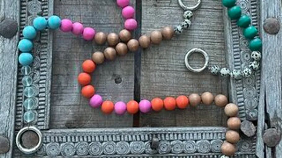 Colourful pearl necklaces lie on a grey wooden background.