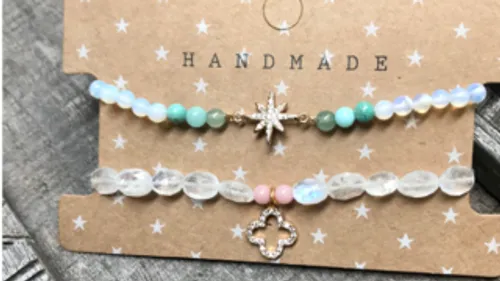Zwei handgemachte Armbänder auf einem Karton mit Sternen.